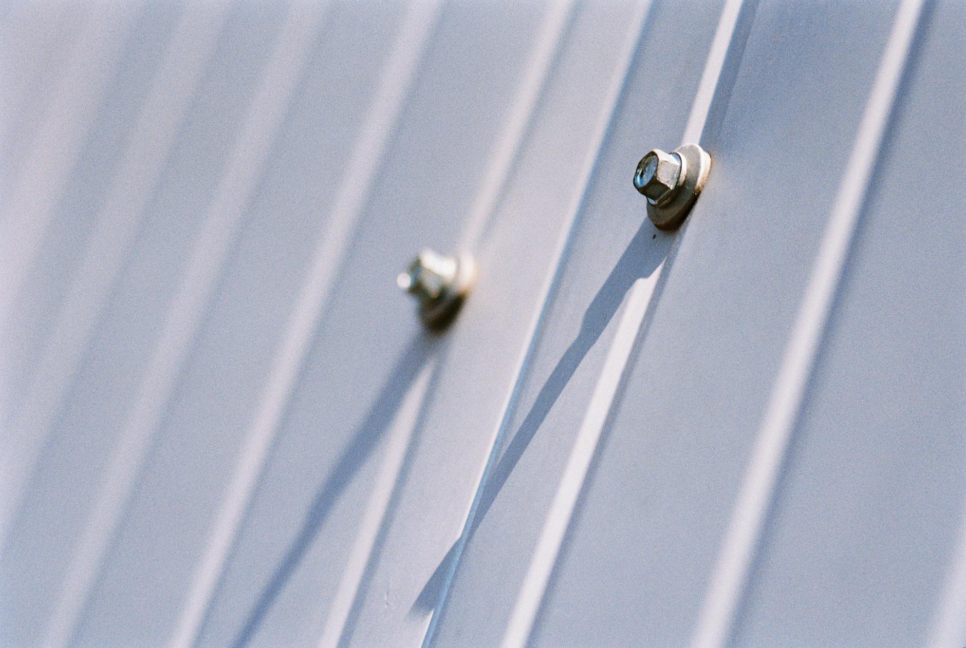 Detailed view of metal screws securing a steel sheet, highlighting durability.