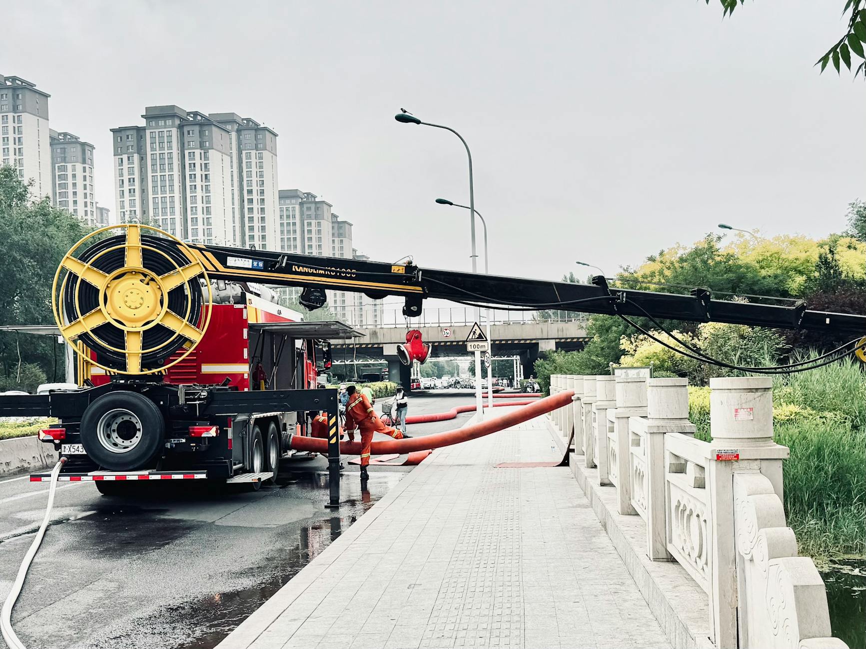 Flood management team operating machinery in urban area for water drainage.